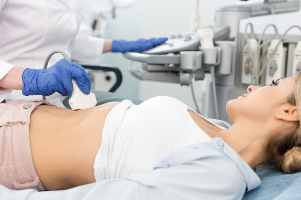 doctor examining stomach of beautiful patient with ultrasound scan in clinic
