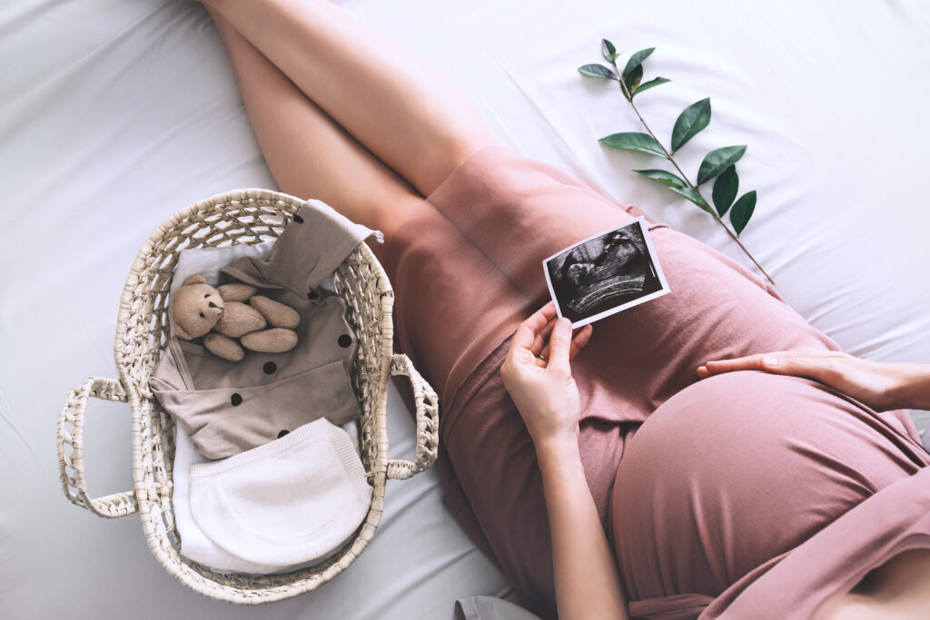 Pregnant woman in dress with ultrasound image. Expectant mother waiting for baby during pregnancy.